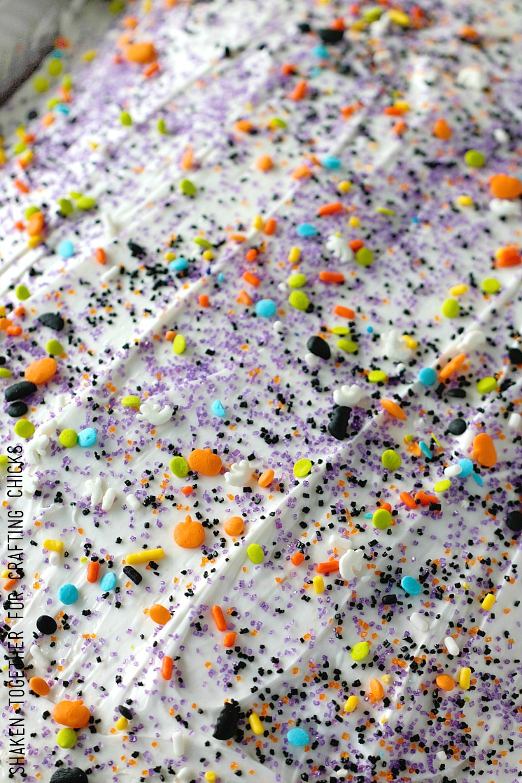 Decorate the top of this Easy Fruity Halloween Poke Cake with tons of sugar and Halloween sprinkles!