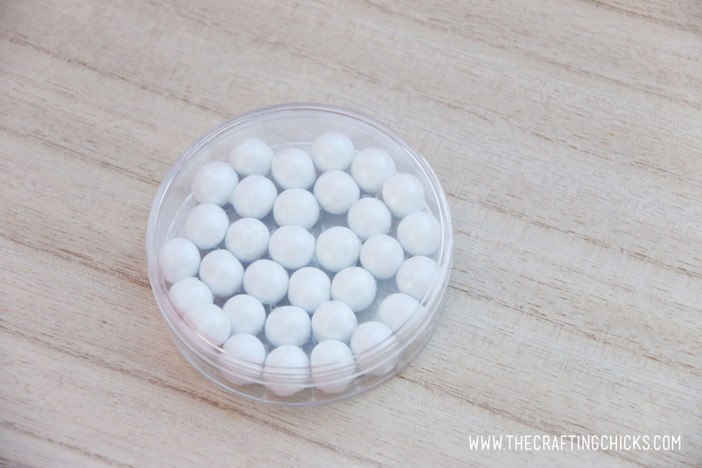 Clear round favor container filled with white Sixlets