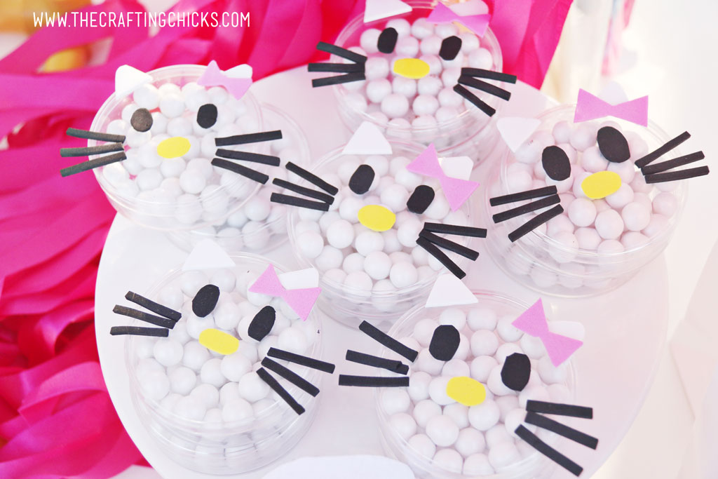 Small clear candy dishes filled with white round candies and decorated to look like Hello Kitty with foam stickers