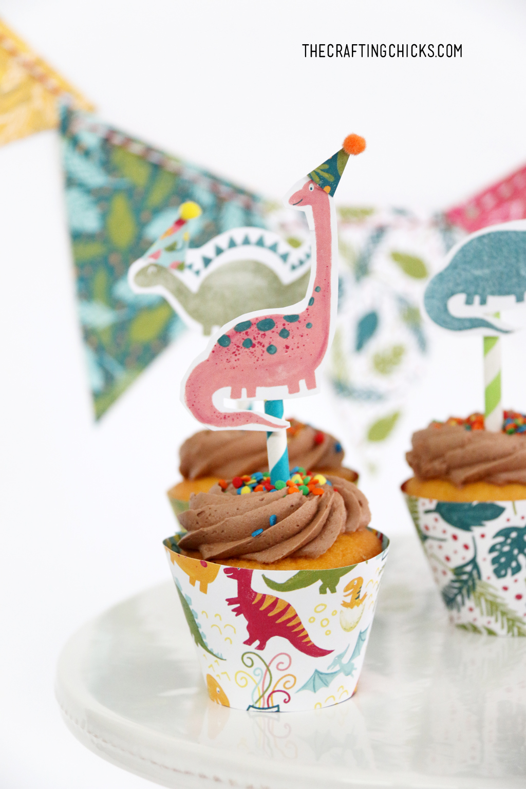 Hand stamped dinosaurs with party hats glued onto stripped paper straws for cupcake toppers.