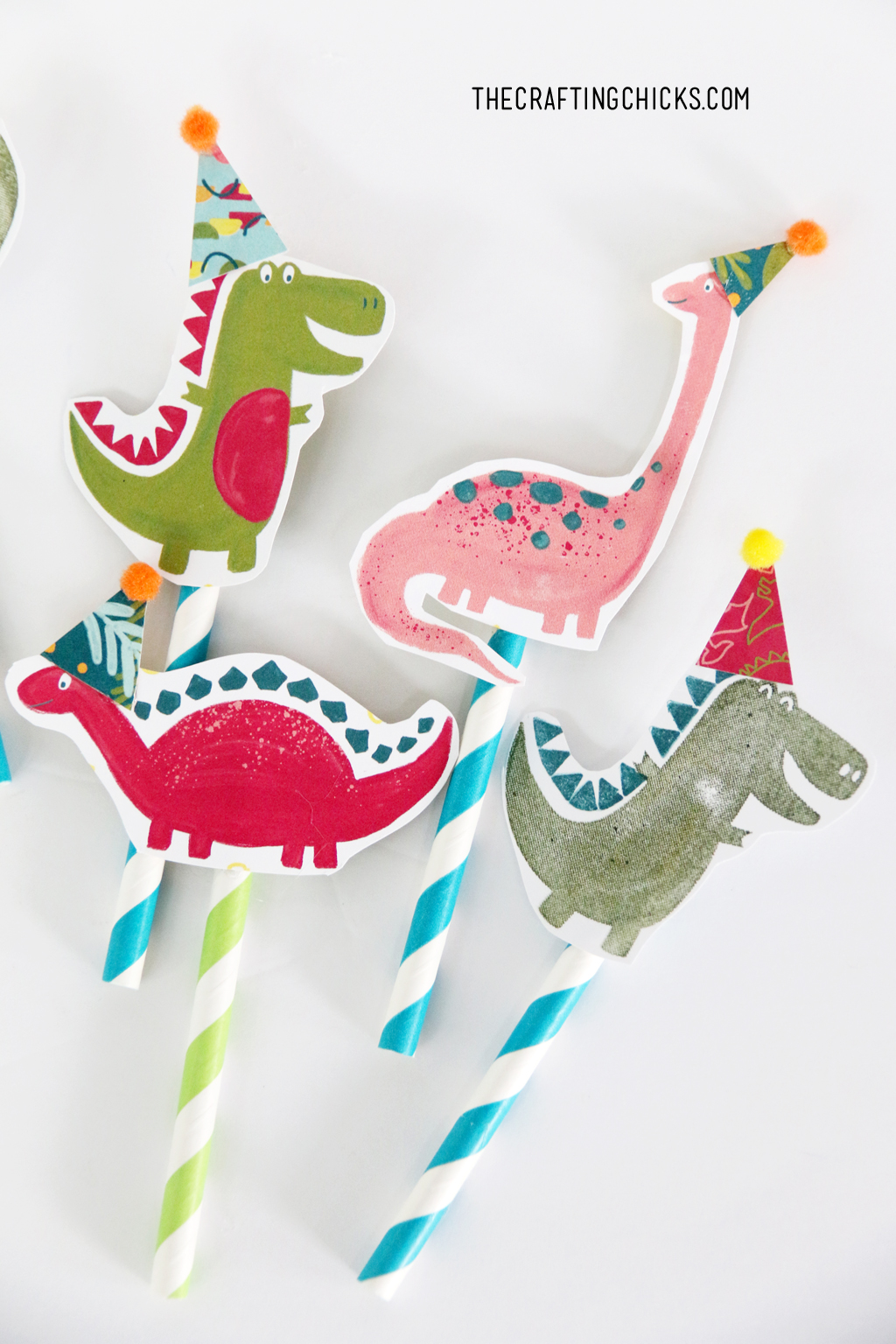 Hand stamped dinosaurs with party hats glued onto stripped paper straws for cupcake toppers.