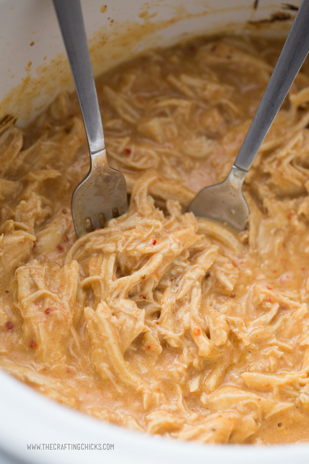 Using forks to pull apart the Crockpot Fiesta Ranch Chicken breast to shred the chicken