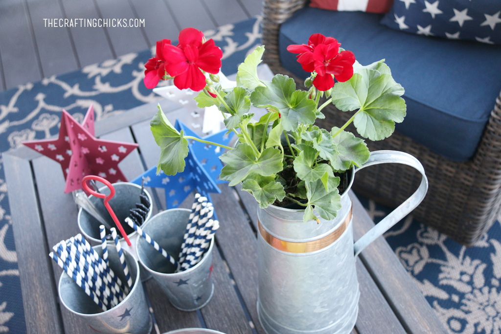 Metal Galvanized pitcher with red geraniums in front of a galvanized tray with glass pitcher of lemonade.