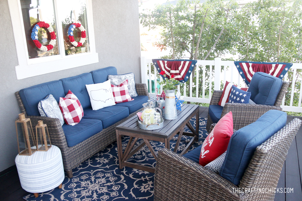 Backyard deck with dark wicker furniture and pops of red, white and blue patriotic decor.