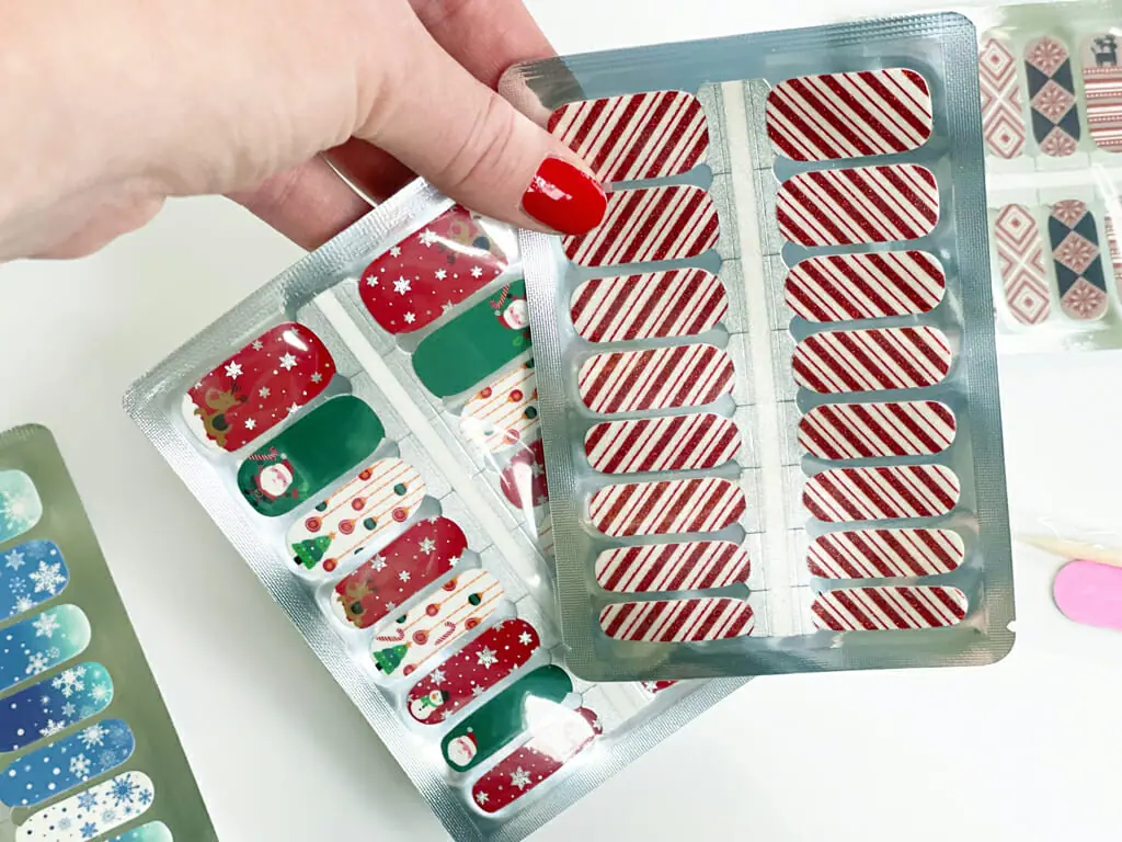 Christmas nail wraps in package being held by hand with red nails.