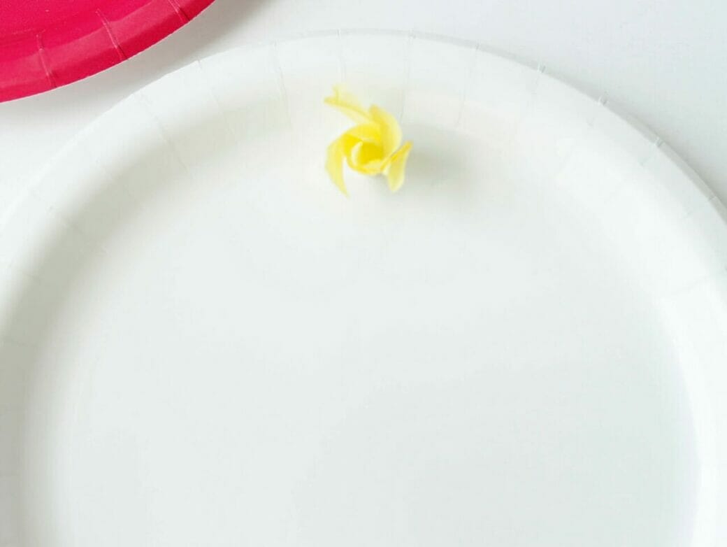 White paper plate with a yellow square of tissue paper on it.