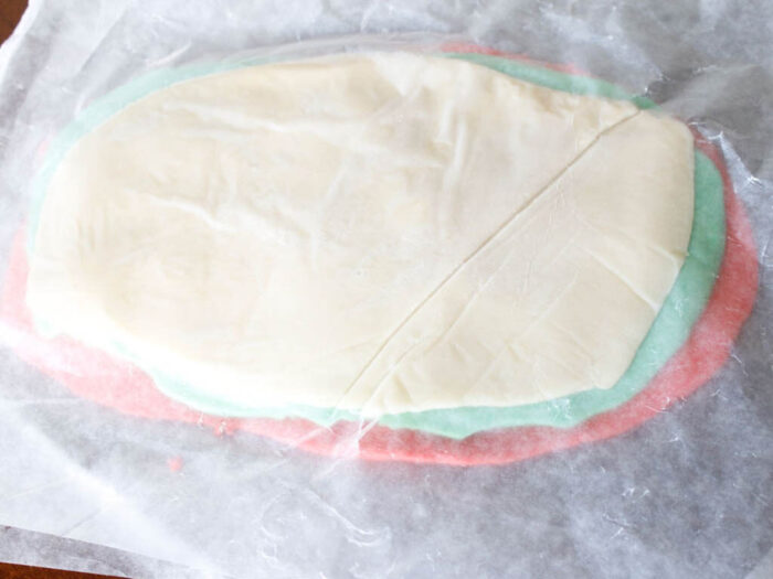 Layered red, green, and white cookie dough on parchment paper.