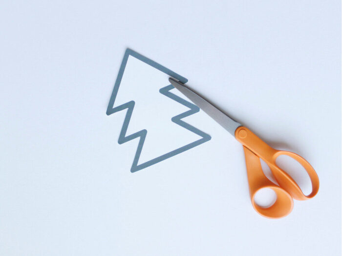 White Christmas tree template cut out with a pair of scissors for Hand-Sewn Paper Plate Christmas Tree Craft for Kids