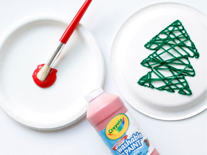 Red paint with a kids paintbrush and the finished Hand-sewn christmas tree paper plate craft.