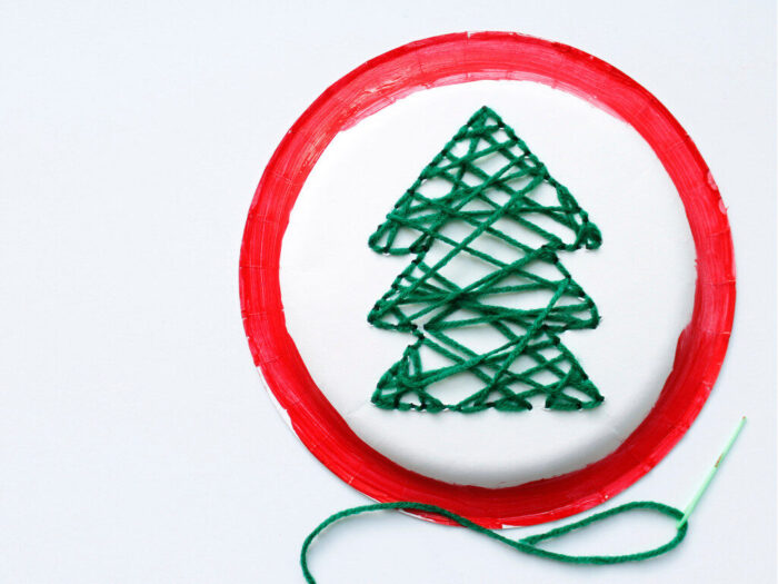 Hand-Sewn Paper Plate Christmas Tree Craft for Kids with red paint around the edges and green yarn christmas tree