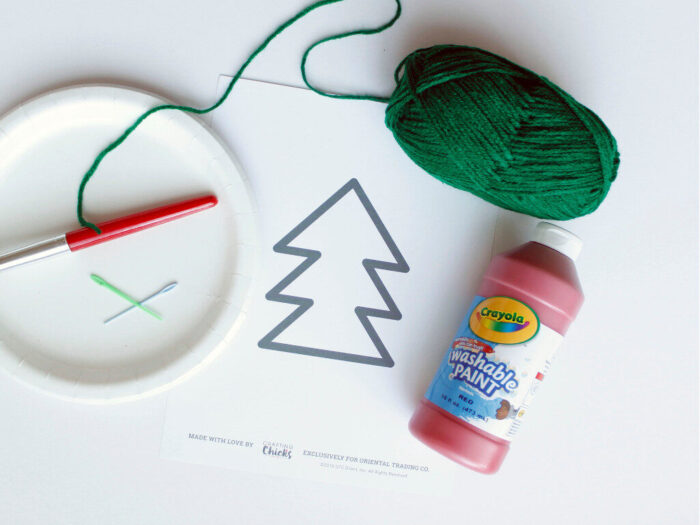 Paper plate paint brush, safe plastic lacing needles, tree template, green yarn, and red paint to make a hand-sewn Christmas tree paper plate craft