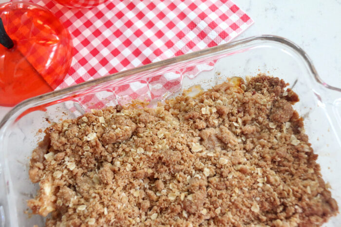 Baked apple crisp with golden brown oat topping in a baking dish.