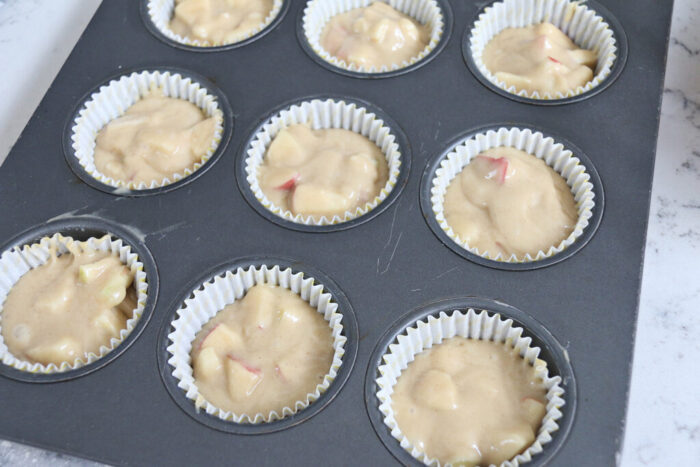 Apple crumble muffin batter in muffin tins lined with paper liners