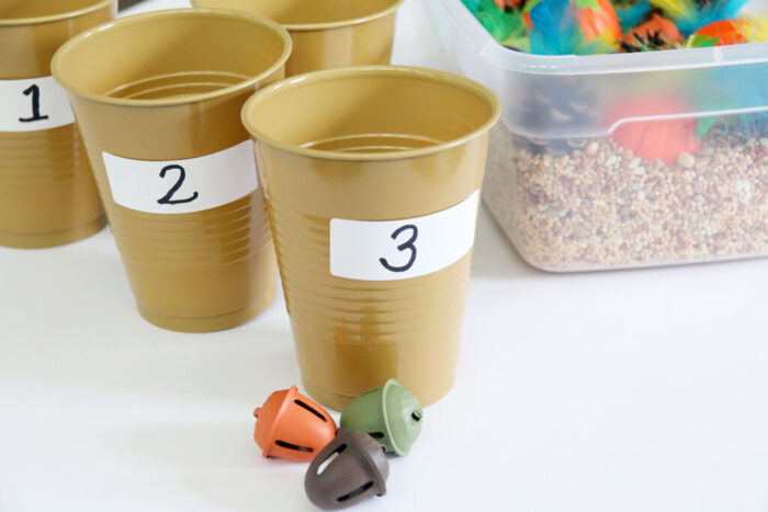 Gold cups and acorn bells outside of the fall sensory bin