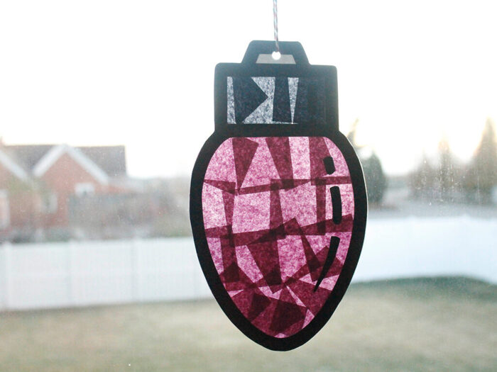 DIY Christmas light suncatchers hanging on a sunny window.